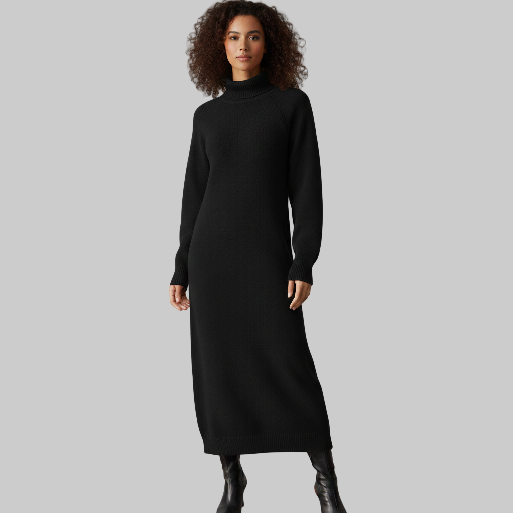 Kobieta ubrana w długą czarną sukienkę z dzianiny z golfem i długimi rękawami, w połączeniu z czarnymi kozakami do kolan, pokazana od przodu na szarym tle.