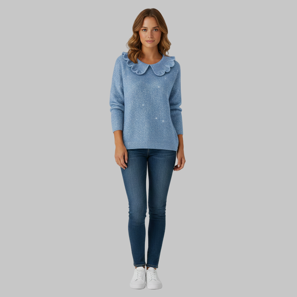Niebieski sweter damski z falistym kołnierzem w połączeniu z niebieskimi dżinsami i białymi trampkami.
