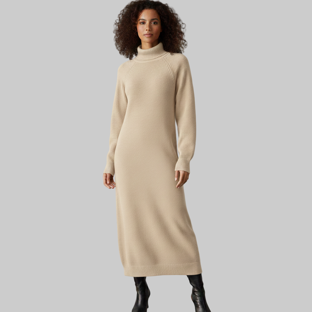 Kobieta ubrana w długą beżową sukienkę z dzianiny z golfem i długimi rękawami, w połączeniu z czarnymi kozakami do kolan, pokazana od przodu na szarym tle.