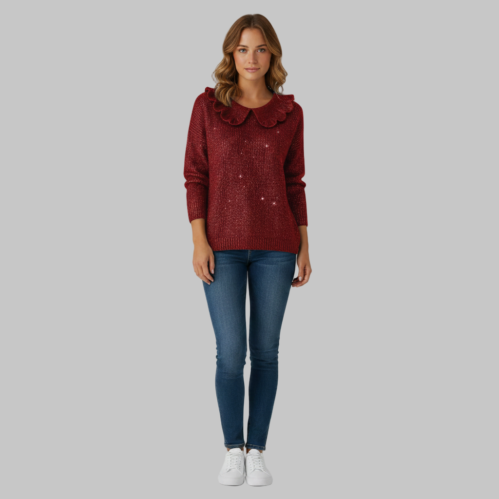 Czerwony sweter damski z falbanami w połączeniu z niebieskimi dżinsami i białymi trampkami.
