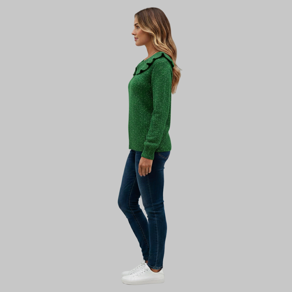 Profil z boku zielonego swetra z falistym kołnierzem w połączeniu z dopasowanymi niebieskimi dżinsami.
